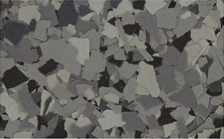 A close-up view of irregularly shaped gray plastic flakes scattered across a surface.