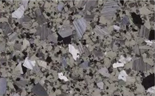 A close-up view of a metallic surface with irregular, shiny, and matte crystalline grain patterns.